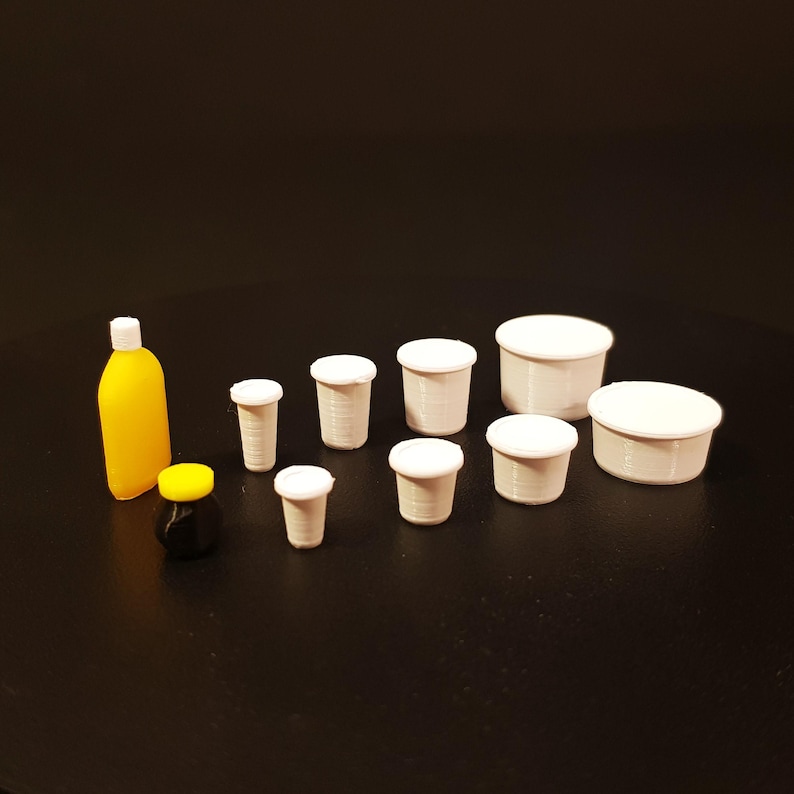 May include: A set of miniature white plastic cups and bowls, a small yellow and black jar, and a small orange bottle.