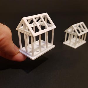 Puede incluir: Dos casas modelo blancas en miniatura con marcos abiertos, que muestran la estructura interior del techo y las paredes. Las casas son de plástico y tienen aproximadamente 7,5 cm de altura.