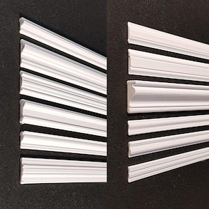 Puede incluir: Un conjunto de diez molduras decorativas blancas. Las molduras están dispuestas en dos filas de cinco, con las piezas de cada fila aumentando de tamaño de izquierda a derecha.