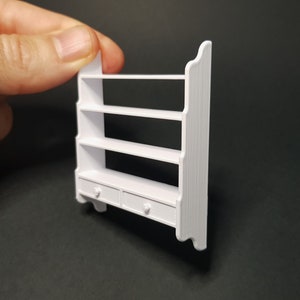 May include: White wooden wall shelf with three shelves and two drawers. The shelf has a simple, farmhouse style.