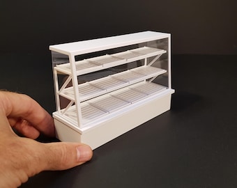 以下が含まれることがあります： 白いガラス棚と白いベースが付いた白いディスプレイケース。ケースは4段で、プラスチック製です。
