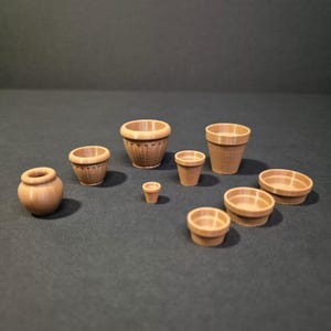Puede incluir: Una colección de diez macetas y cuencos en miniatura de color marrón claro de diversas formas y tamaños. El conjunto incluye macetas redondeadas, macetas cónicas con laterales texturizados y cuencos poco profundos, con acabado mate.