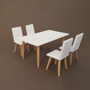 May include: A white dining table set with four chairs. The table and chairs have a modern design with wooden legs.