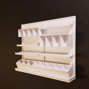 Puede incluir: Estantería blanca de pared con múltiples estantes y compartimentos. La unidad tiene un estante inferior con varios contenedores de plástico blancos.