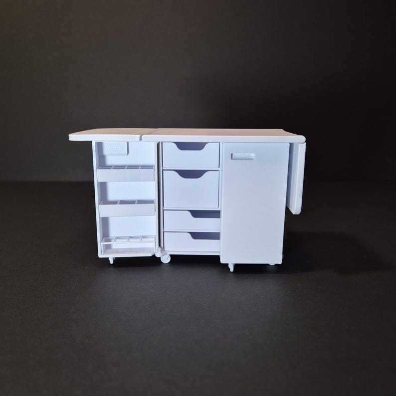 May include: A white miniature cabinet with multiple storage options. It features a pull-out shelf, three drawers, a cabinet door, and a side extension. The cabinet is on wheels and has a clean, minimalist design.