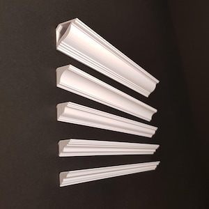 May include: Five white decorative molding pieces of varying sizes and shapes, arranged vertically against a black background.