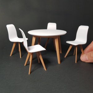 Könnte beinhalten: Ein weißer runder Tisch mit vier weißen Stühlen. Tisch und Stühle haben Holzbeine.