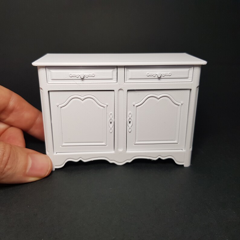 May include: White painted wooden cabinet with two drawers and two doors. The cabinet has a decorative, scalloped base and ornate hardware.