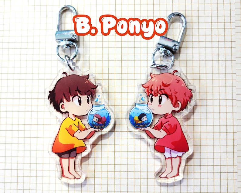 May include: Two clear acrylic keychains featuring anime-style characters holding fishbowls. One character wears a yellow outfit, the other a red outfit. Each keychain has a silver-colored clasp. The text "B. Ponyo" is at the top.