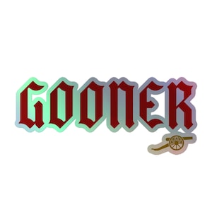 Può includere: Un adesivo rosso e bianco con la parola "Gooner" in un font gotico. L'adesivo ha una finitura olografica e presenta una piccola grafica di un cannone.