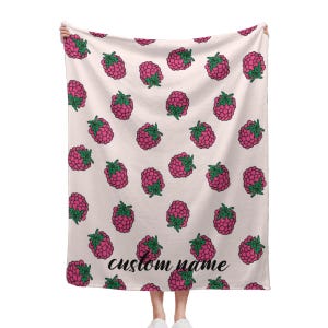 Könnte beinhalten: Eine rosa-grüne Fleece-Decke mit Himbeer-Muster. Die Decke hat den Text "custom name" aufgedruckt.