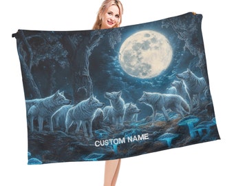 Puede incluir: Una manta de tiro azul oscuro y negro con una luna llena y una manada de lobos blancos en un entorno de bosque. La manta tiene el texto "CUSTOM NAME" impreso en ella.
