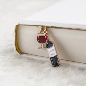 Op de afbeelding: Gouden bladwijzer met een rood wijnglas en een wijnflesbedel. De flesbedel heeft de tekst "Lafite 1983" erop.