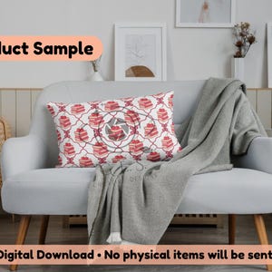 May include: A decorative rectangular pillow with a repeating pattern of red cakes on a white background, accented with a red geometric design. The pillow is placed on a light gray sofa with a gray blanket.