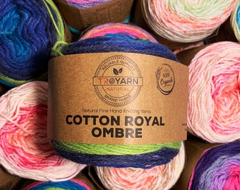 May include: Close-up of several skeins of cotton yarn in various ombre colorways. The yarn is labeled "Cotton Royal Ombre" and "Troyarn Natural Brand Yarns".