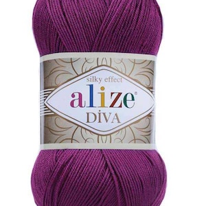 Pode incluir: Novel de fio Alize Diva roxo vibrante. O rótulo diz "efeito sedoso" e apresenta o nome da marca. O fio é bem enrolado, mostrando uma textura suave. Ideal para projetos de tricô e crochê.