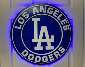 Puede incluir: Un logotipo azul y blanco de los Dodgers de Los Angeles con una luz LED azul alrededor del borde. El logotipo está en una puerta blanca.