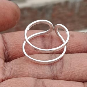 May include: A silver ring with a double band design. The ring is simple and elegant, and would make a great gift for any occasion.
