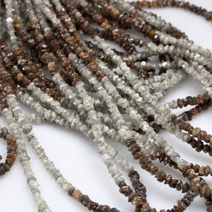 May include: A strand of rough, uncut diamonds, also known as raw diamonds, in various shades of brown and grey. The diamonds are strung together on a thin thread, creating a delicate and unique necklace.