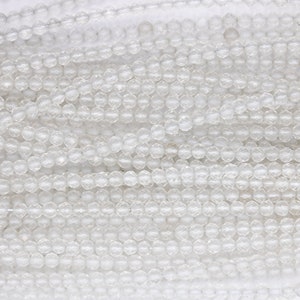 Peut inclure: Gros plan sur un brin de perles de verre transparentes. Les perles sont rondes et ont une texture facetée.