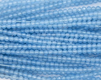 May include: Close-up of strands of light blue faceted beads. The beads are small, round, and have a sparkling, textured surface. The beads are strung together on thin, white cords, creating a delicate and elegant appearance. The beads are a soft, pastel blue color.