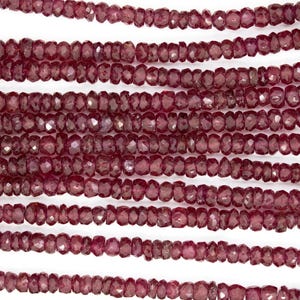 Könnte beinhalten: Eine Strähne tief roter Rubinperlen, facettiert und poliert, mit leicht unregelmäßiger Form. Die Perlen sind in einer durchgehenden Linie aufgereiht und erzeugen einen schönen und eleganten Look.