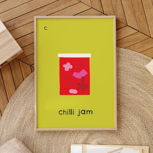 May include: A framed print with a yellow background and a red jar with pink and red shapes inside. The text "c" is in the top left corner and "chilli jam" is at the bottom.