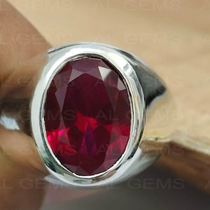 Op de afbeelding: Een zilveren ring met een grote, ovale, rode edelsteen.