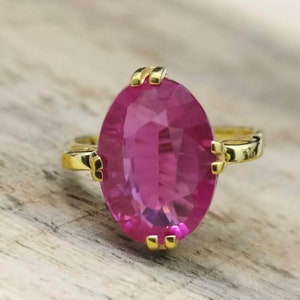 Peut inclure: Une bague en or avec une grande pierre précieuse rose de forme ovale. La bague a une bande simple et la pierre précieuse est sertie à griffes.