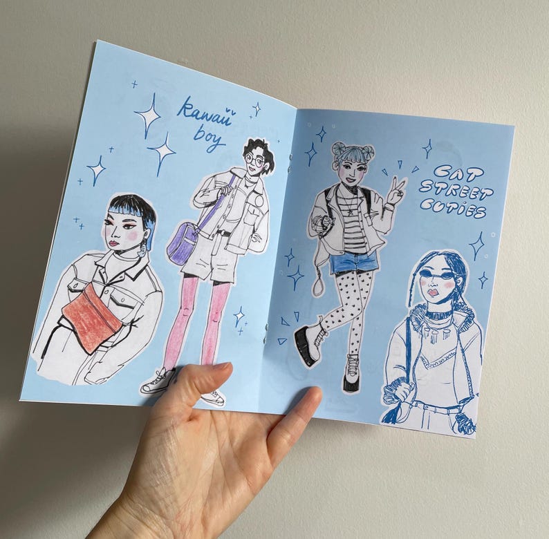 Pode incluir: Um livreto ilustrado azul e branco com o texto "Kawaii boy" e "Cat Street Cuties". O livreto apresenta ilustra&ccedil;&otilde;es de quatro pessoas vestindo roupas diferentes.