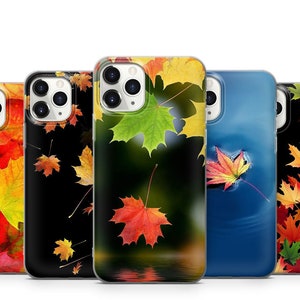 May include: A collection of phone cases featuring autumn leaf designs. The cases display vibrant red, yellow, and green maple leaves against various backgrounds, including black and a water reflection. The cases are designed to fit a smartphone.