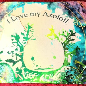 Könnte beinhalten: Ein farbenfrohes Mousepad mit einem Axolotl-Design und dem Text "I Love my Axolotl". Das Design zeigt einen hellbeige Axolotl mit grünen und blauen Akzenten vor einem lebendigen, abstrakten Hintergrund.