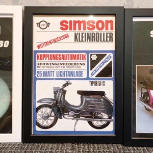 May include: Three framed vintage Simson scooter advertisements. The posters feature illustrations of the scooters in various colors, including blue, black, and pink. The frames are black and white, and the text includes "Simson" and scooter model names.