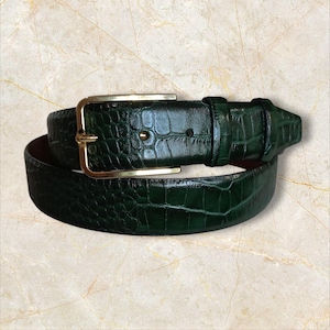 May include: A dark green belt with a textured, crocodile-like pattern. The belt features a gold-colored rectangular buckle and a matching belt loop. The leather belt is designed for waist sizes up to 40 inches.