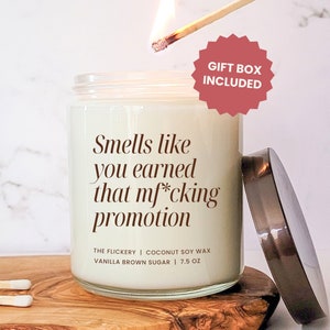 May include: A glass candle jar with a white label that reads "Smells like you earned that mf*cking promotion". The candle is a vanilla brown sugar scent and is made with coconut soy wax. The candle is 7.5 oz and comes in a gift box.