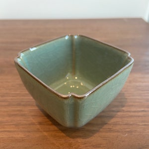 Könnte beinhalten: Eine quadratische, hellgrüne Keramikschüssel mit braunem Rand. Die Schüssel hat eine strukturierte Oberfläche und ist etwas breiter als hoch.