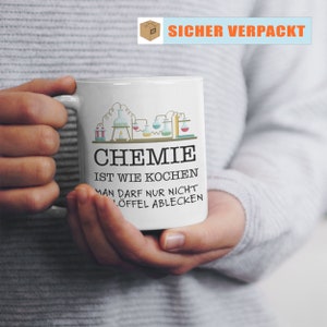 Puede incluir: Taza de cer&aacute;mica blanca con un dise&ntilde;o tem&aacute;tico de qu&iacute;mica, con vasos de precipitados y matraces. La taza tiene el texto "CHEMIE IST WIE KOCHEN MAN DARF NUR NICHT L&Ouml;FFEL ABLECKEN". La taza es sostenida por una persona.