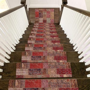 May include: A staircase with dark wood steps and a patterned rug runner. The runner features a patchwork design with shades of red, burgundy, and beige. White balusters and a dark wood handrail frame the stairs.