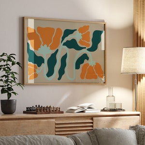 Pu&ograve; includere: Una stampa incorniciata di un design floreale stilizzato con fiori arancioni e turchesi su uno sfondo beige. La stampa &egrave; appesa a un muro sopra un mobile in legno con un divano di fronte.