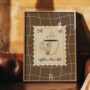Op de afbeelding: Ingelijste kunstdruk met een koffiethema. Het kunstwerk toont een koffiekopje met een persoon die een ladder beklimt, stoom die uit de kop opstijgt, en de tekst "coffee, then life". De print heeft een bruin en wit kleurenschema.
