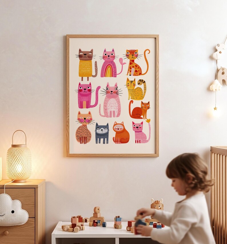 May include: A framed art print featuring a collection of colorful, cartoon-style cats. The cats are depicted in various poses and colors, including pink, orange, yellow, and brown. The artwork is displayed in a light-colored wooden frame, suitable for a child's room.