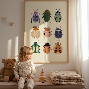 Könnte beinhalten: Ein gerahmter Druck mit neun farbenfrohen Insektenillustrationen. Die Insekten sind in verschiedenen Farben, darunter Grün, Blau, Orange und Rosa, auf einem cremefarbenen Hintergrund dargestellt. Ein junges Kind in einem floralen Strampler sitzt auf einer Bank mit einem Teddybär und einem Holzspielzeug zum Stapeln.