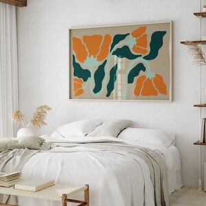 Pu&ograve; includere: Un letto bianco con una coperta beige e un cuscino beige. Una stampa incorniciata di fiori arancioni e verdi &egrave; appesa sopra il letto.