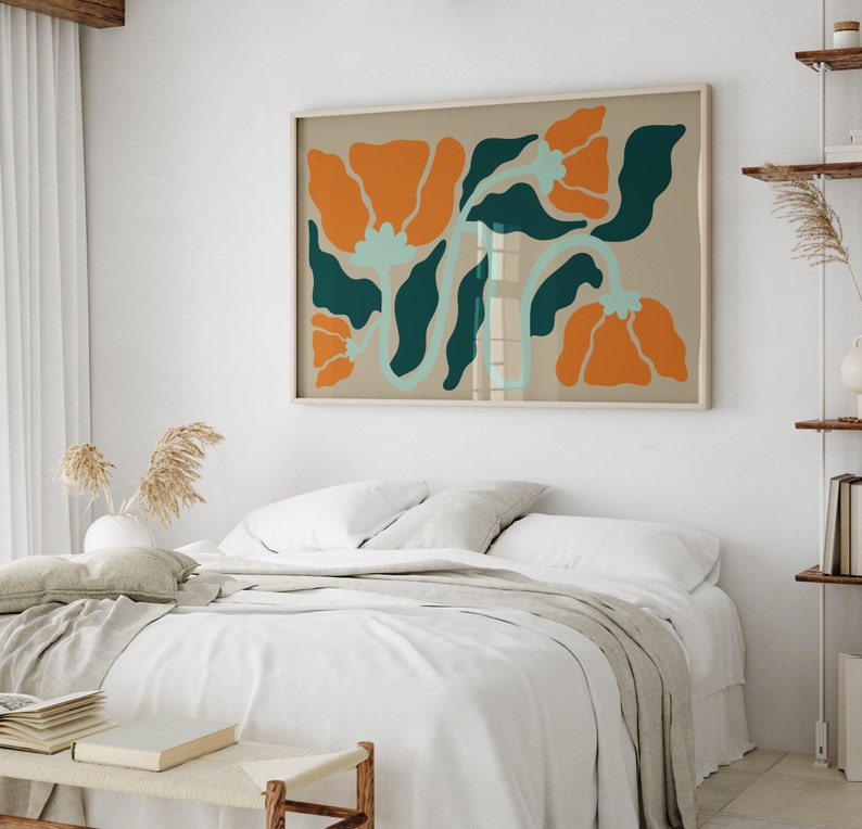Pu&ograve; includere: Un letto bianco con una coperta beige e un cuscino beige. Una stampa incorniciata di fiori arancioni e verdi &egrave; appesa sopra il letto.