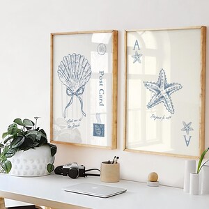 May include: Two framed art prints with beach-themed illustrations. One features a blue seashell with a bow and the text "Meet me at the Beach". The other shows a blue starfish and the text "Bonjour for ever".