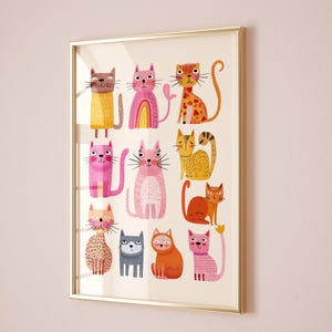 May include: A framed art print featuring a collection of whimsical cat illustrations. The cats are depicted in various colors, including pink, orange, and yellow, with unique patterns and expressions. The artwork is set against a cream background and framed in a gold-colored frame.