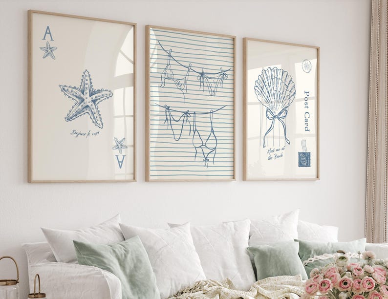 May include: Three framed art prints with a coastal theme. The prints feature blue line drawings of a starfish, lingerie on a clothesline, and a seashell. The starfish print includes the text "Bonjour le mer".