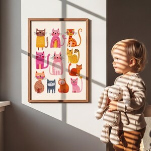 May include: A framed art print featuring a collection of colorful, stylized cat illustrations. The cats are depicted in various poses and colors, including orange, pink, yellow, and blue, against a cream background. The frame is a light brown wood.
