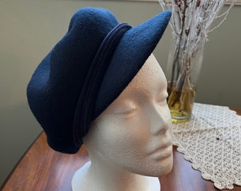 May include: A navy blue felt hat with a wide brim and a black band around the crown.