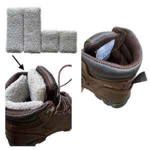 May include: Brown leather work boots with a soft, light-colored lining. The image also shows gray wristbands. The boots have a rugged design with laces and a durable sole, suitable for outdoor work or activities.